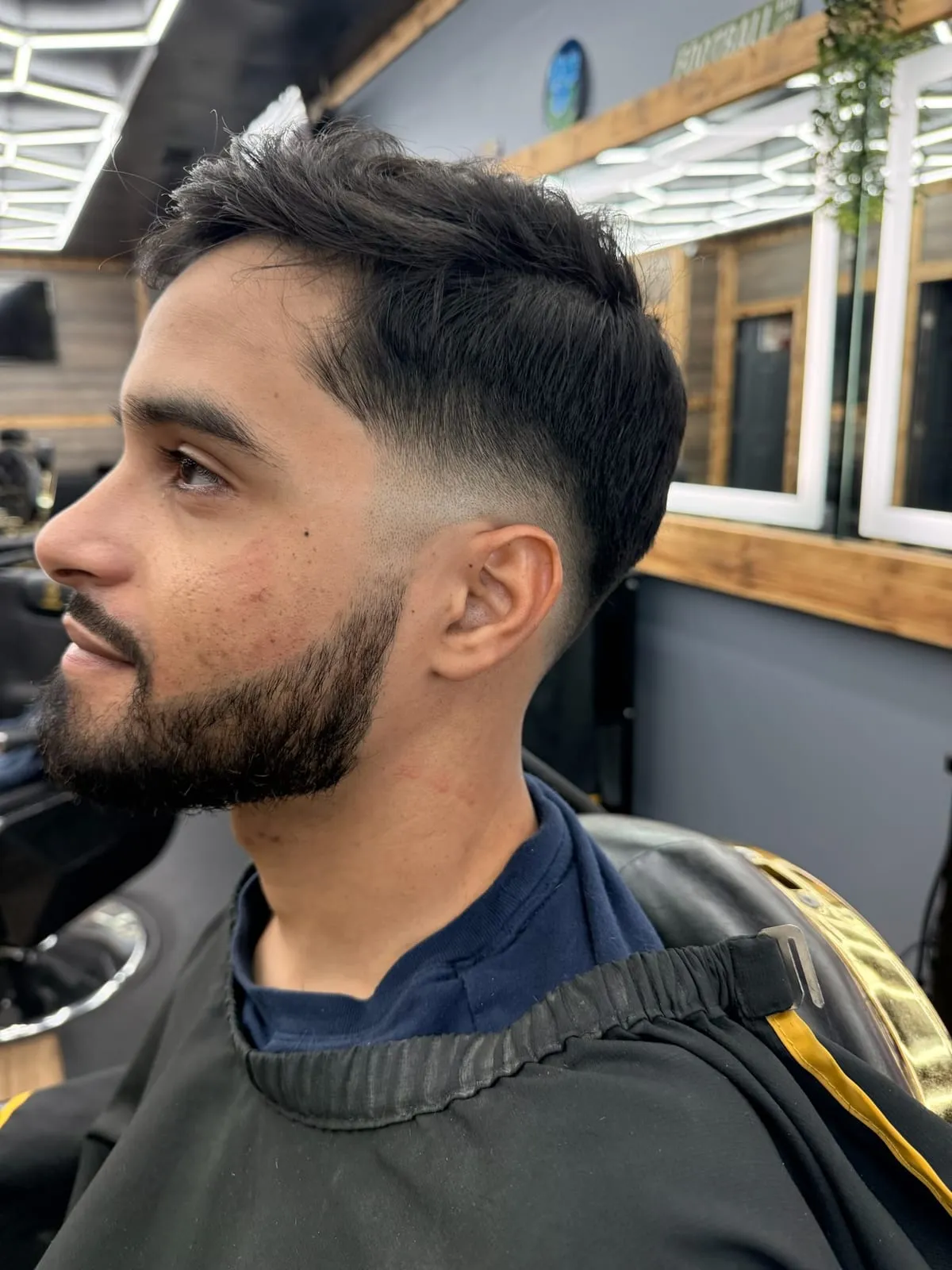 Man in profile with a swept-back top, a skin fade and a neatly trimmed beard