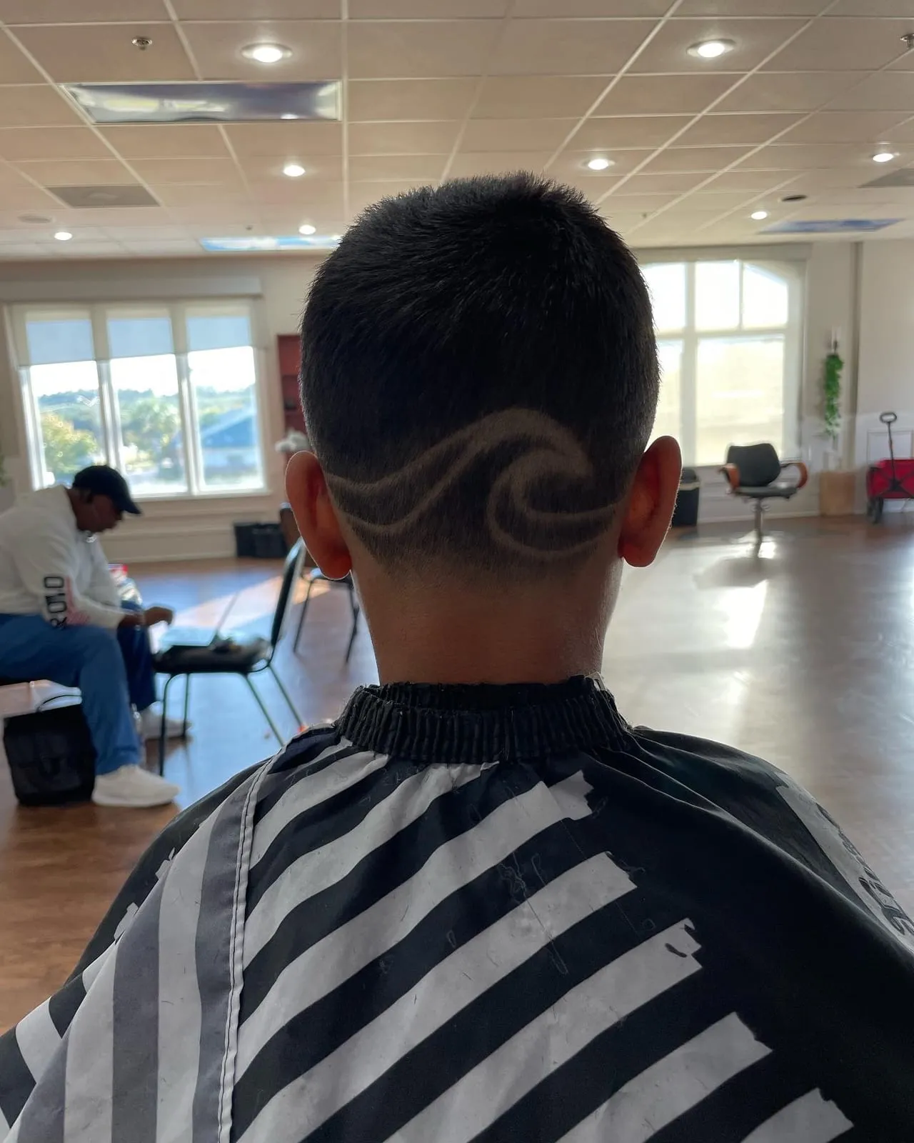 Boy seen from behind with a wave design cut into a short, faded back and sides